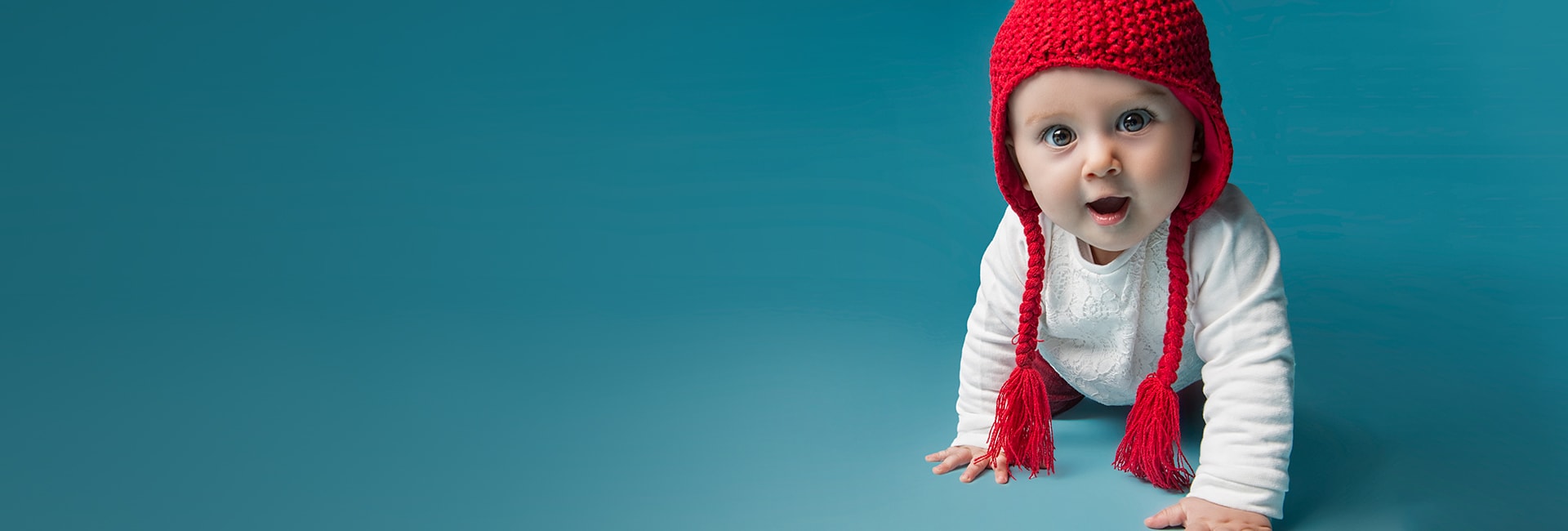 Photo of baby crawling with a red hat on
